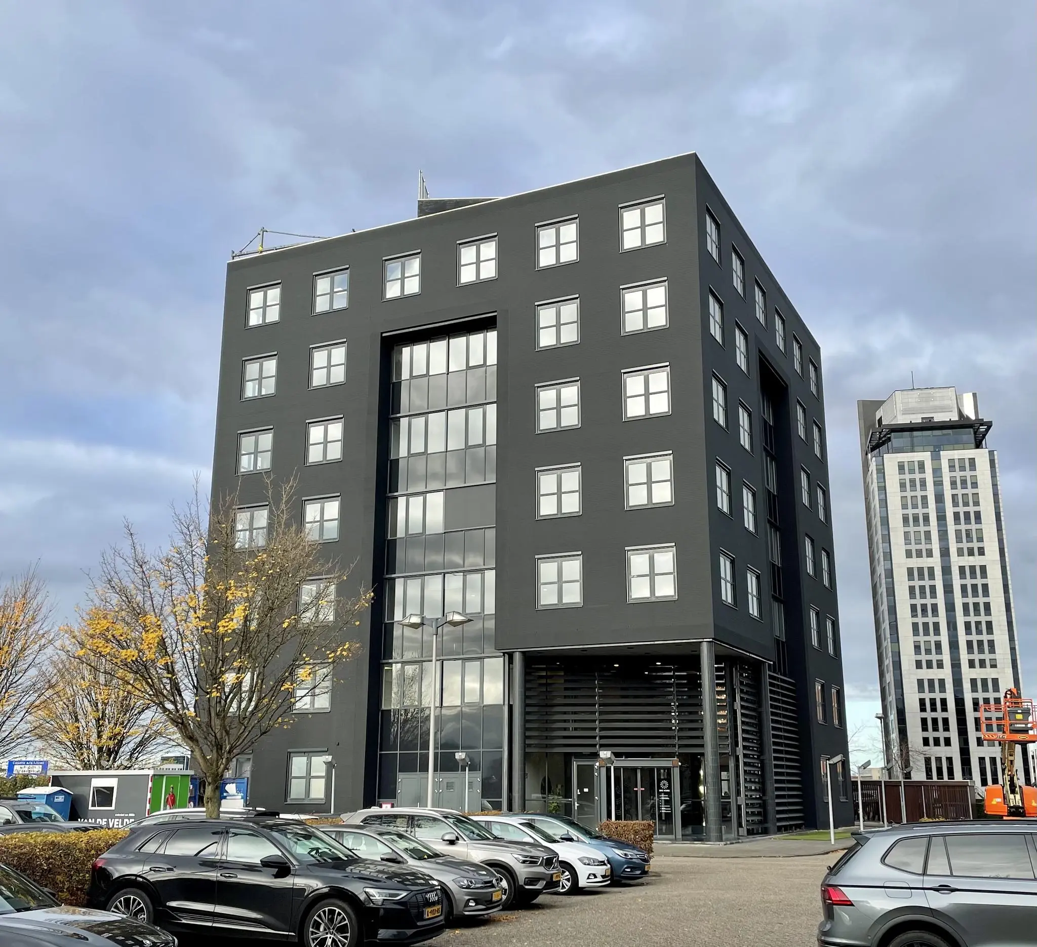 Zwart kantoorgebouw aan het Rivium Quadrant met geparkeerde auto's op de voorgrond.